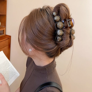 Close-up of amber beads claw clip holding a low bun hair style for women