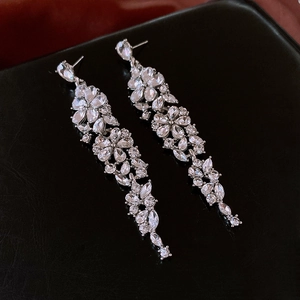 Close-up of elegant silver flower tassel earrings with sparkling zircon on black leather
