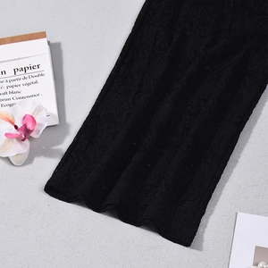 Detailed close-up of intricate hollow lace floral patterns on black sheer trousers