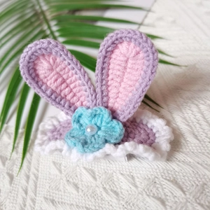 Close-up of handmade crochet purple rabbit ears hair clip with blue flower and pearl