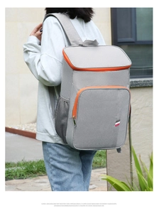 Vue détaillée d'un sac à dos isotherme gris avec fermetures orange porté à l'extérieur