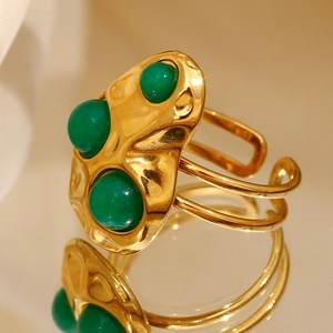 Macro detail of 18K gold plated ring with hammered texture and three green gemstones