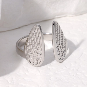 Detailed macro view of silver stainless steel open ring with intricate wing texture