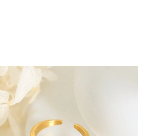 Close-up of a gold-plated adjustable open ring featuring a thick minimalist band design
