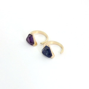 Golden open rings set featuring hexagonal amethyst and lapis lazuli stones on white background