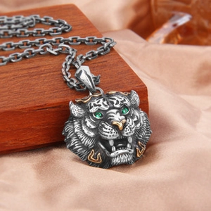 Détail d'un pendentif tigre rétro avec yeux en pierres vertes et accents dorés sur chaîne