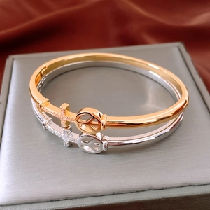 Macro detail of 18K gold plated bangle set with diamond cross and peace symbol motifs