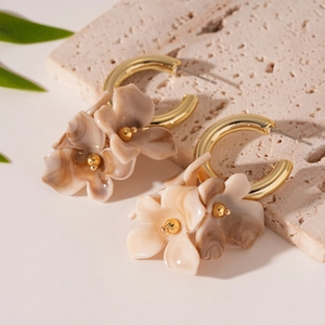 Détail de boucles d'oreilles créoles dorées en C avec fleurs en résine beige vintage