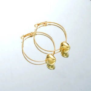 Macro shot of gold hollow heart charms on large hoop earrings with mirror reflection