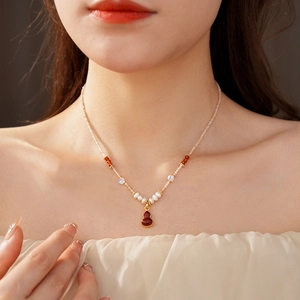 Detail of red agate gourd pendant and freshwater pearl necklace worn by a model
