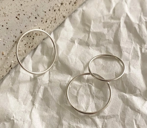 Detailed view of three minimalist 925 silver slim rings on a textured white paper background