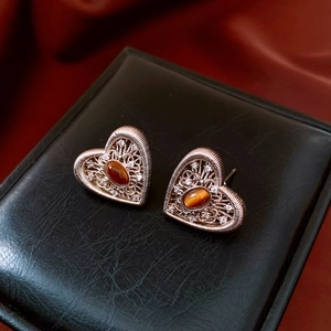 Detail of rose gold filigree heart earrings with zircon and tiger eye stone in a jewelry box