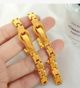 Macro shot of gold watchband style bracelet with horse buckle detail for men and women