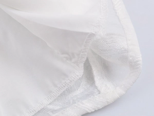 Close-up of precise stitching and hem details on elegant white chiffon dress fabric