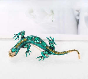 Détail macro de la broche lézard avec émail vert, cristaux et métal doré poli