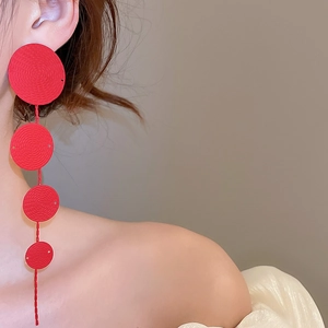Detail of red tiered circular drop earrings with spiral texture on a fashion model