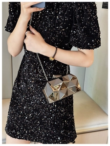 Detail of silver geometric acrylic clutch bag with metal chain on black sequin dress