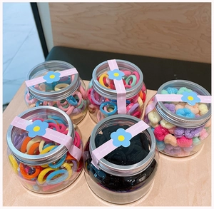 Set of five jars containing colorful elastic hair ties and soft velvet scrunchies for girls