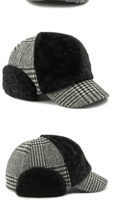 Detail view of winter earflap hat with black and white plaid pattern and faux shearling lining