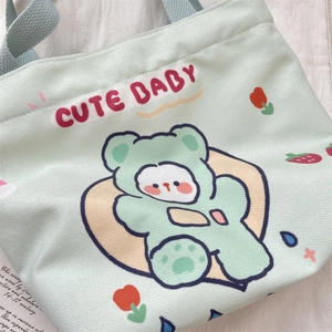 Detail of mint green canvas tote bag featuring cute cartoon bear and CUTE BABY text