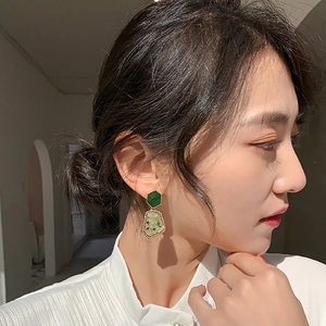 Retro geometric earrings with green stones and botanical design on female model