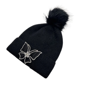 Detail of black knit beanie with faux fur pom and rhinestone butterfly patch