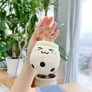 Hand holding a plush boba tea keychain with a cute smiling face and pearl embroidery