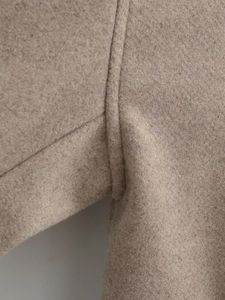 Détail des coutures de haute qualité sur le tissu en laine beige du manteau
