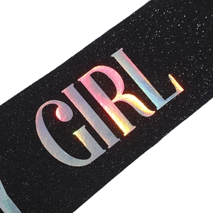 Macro shot of holographic 'GIRL' lettering on black glitter party sash fabric detail