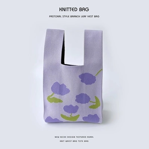 Detailed close-up of pastoral floral knitted tote bag with purple flowers and green leaves