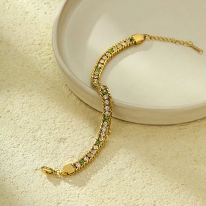 Detail of gold chain bracelet with white and green zircons on a ceramic plate