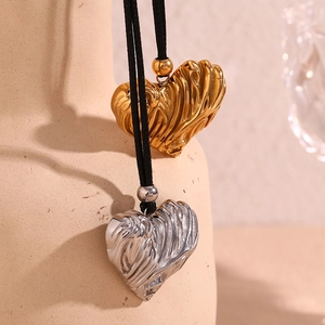 Detail of 3D pleated heart pendants in gold and silver on black leather cords