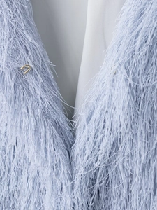 Close-up of light blue jacket featuring soft feather fringes and a metallic hook closure