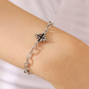Detailed close-up of a silver cross bracelet with black enamel finish on a woman's wrist