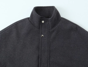 Detail of dark grey wool bomber jacket collar featuring textured fabric and silver snaps