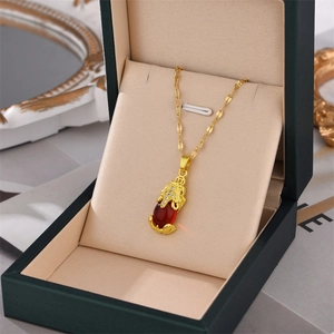 Golden Pi Xiu pendant necklace with a red teardrop stone in a vintage jewelry box