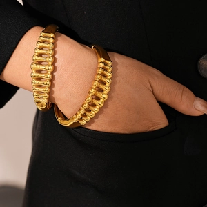 Golden fishbone texture stainless steel open bangle displayed on a black blazer background