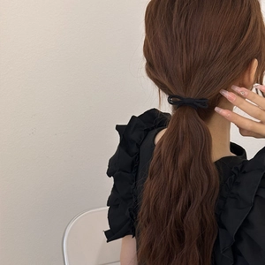 Minimalist black bow hair tie shown on a ponytail from a clean back view perspective