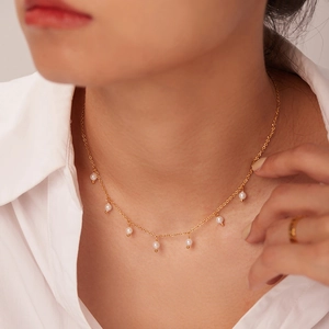 18K gold stainless steel necklace with small white pearl pendants on a model