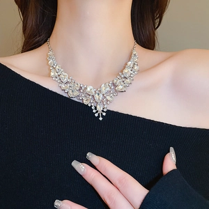 Dettaglio della collana floreale argento con diamanti a goccia su modella in nero