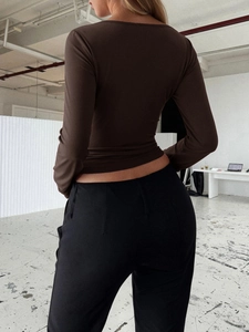 Rear view of woman wearing a fitted brown Y2K long sleeve top and black slim trousers
