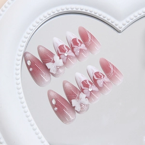 Pink and white cat eye press-on nails with 3D bows and rhinestones on heart mirror tray