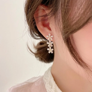 Close-up of golden floral tassel earrings with sparkling zircon petals on a model