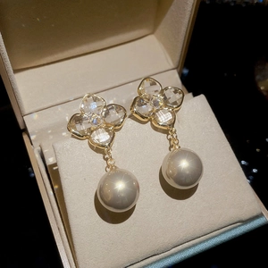Macro shot of gold-plated flower earrings with cubic zirconia and white pearls on jewelry box