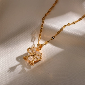 Macro shot of gold-plated heart necklace with bow pendant on white silk fabric