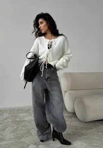 Détail du cardigan blanc tricoté à rubans avec un jean gris large pour un look moderne