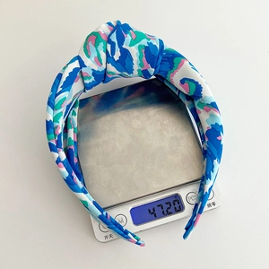 Close-up of a floral knot headband featuring satin fabric with colorful abstract patterns