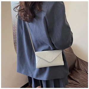 Detail der silbernen Umschlagtasche mit Metallkette, getragen zu einem grauen Blazer