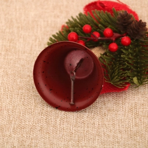 Macro detail of red metal bell with pine needles and cones for Christmas decor