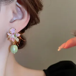 Pink flower earrings with pearls and green drop beads on an elegant model portrait